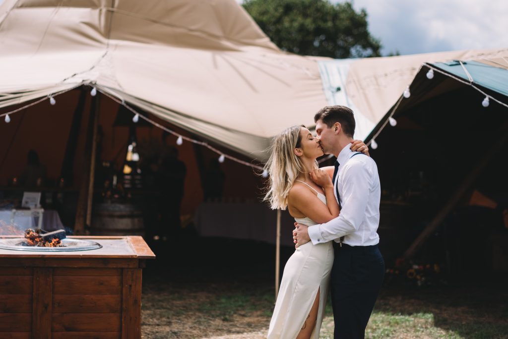 A young married couple are embracing and kissing outside a wedding tipi at The Reid Rooms. A young married couple are embracing and kissing outside a wedding tipi at The Reid Rooms.