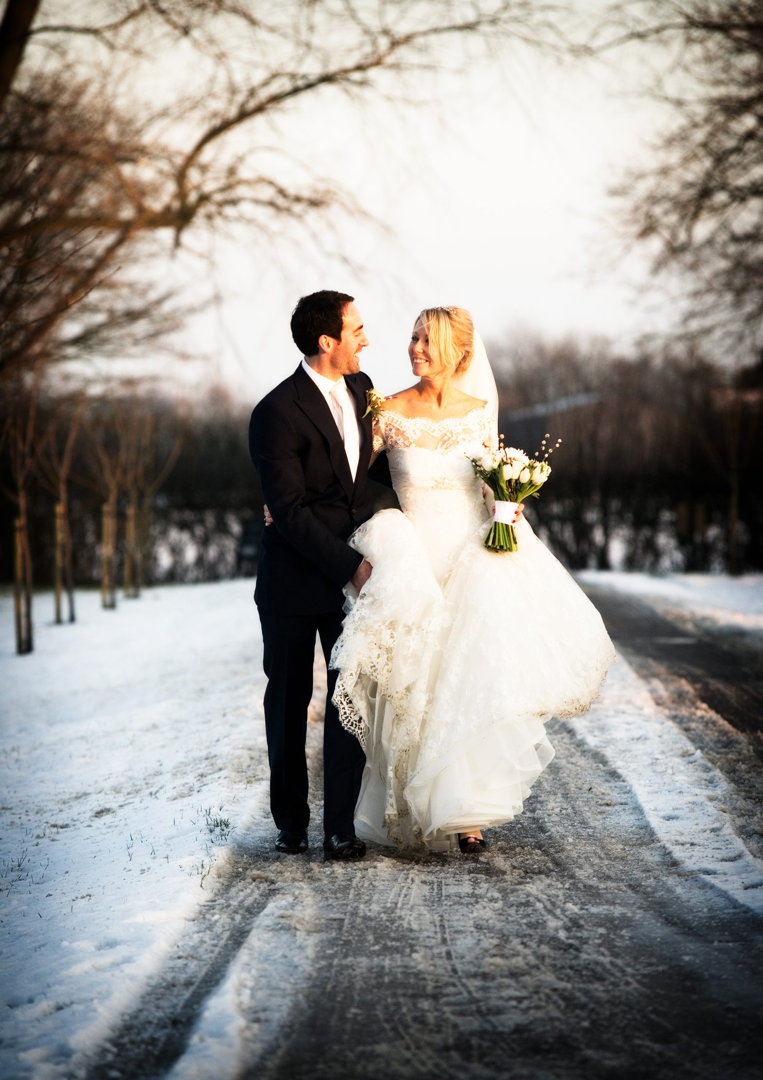 A bride and groom walk down a snowy driveway in the winter at The Reid Rooms.