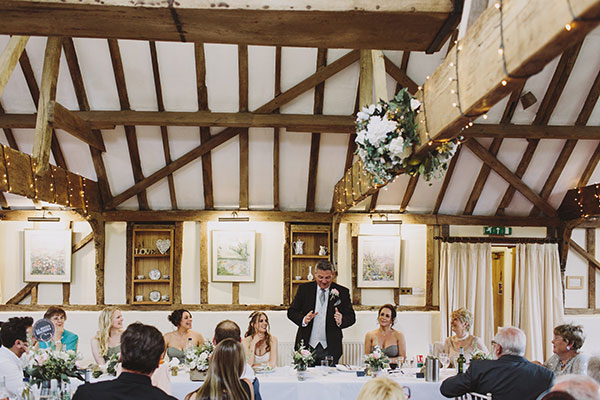 Interior shot of a wedding breakfast at The Reid Rooms. A man is stood behind a table giving a wedding speech. Interior shot of a wedding breakfast at The Reid Rooms. A man is stood behind a table giving a wedding speech.