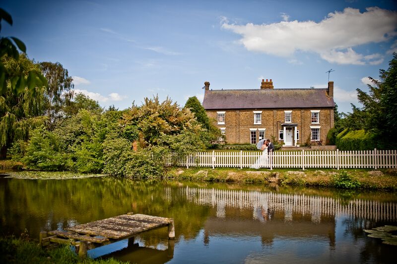 Exterior shot of Marks Hall Farmhouse, the on-site accommodation at The Reid Rooms. A large brick building with a moat and gardens surrounding it. Exterior shot of Marks Hall Farmhouse, the on-site accommodation at The Reid Rooms. A large brick building with a moat and gardens surrounding it.