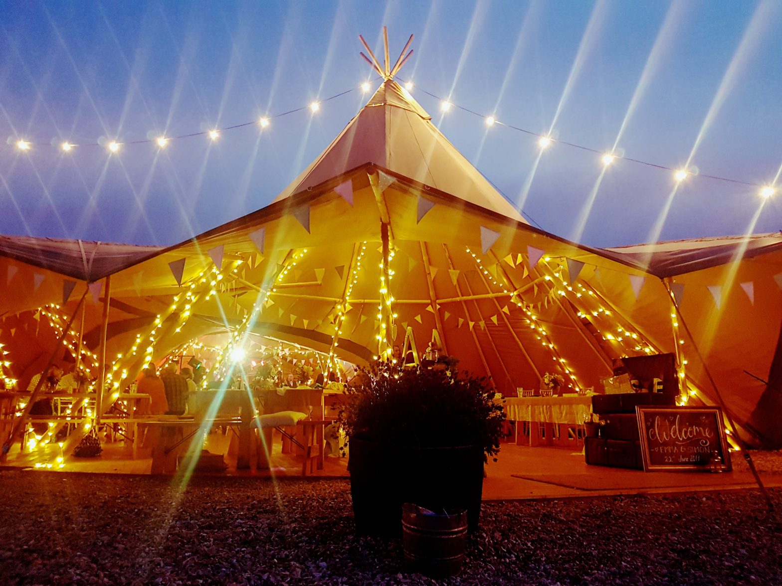 Exterior shot of a wedding tipi at The Reid Rooms at dusk lit by festoon lighting and fairy lights.