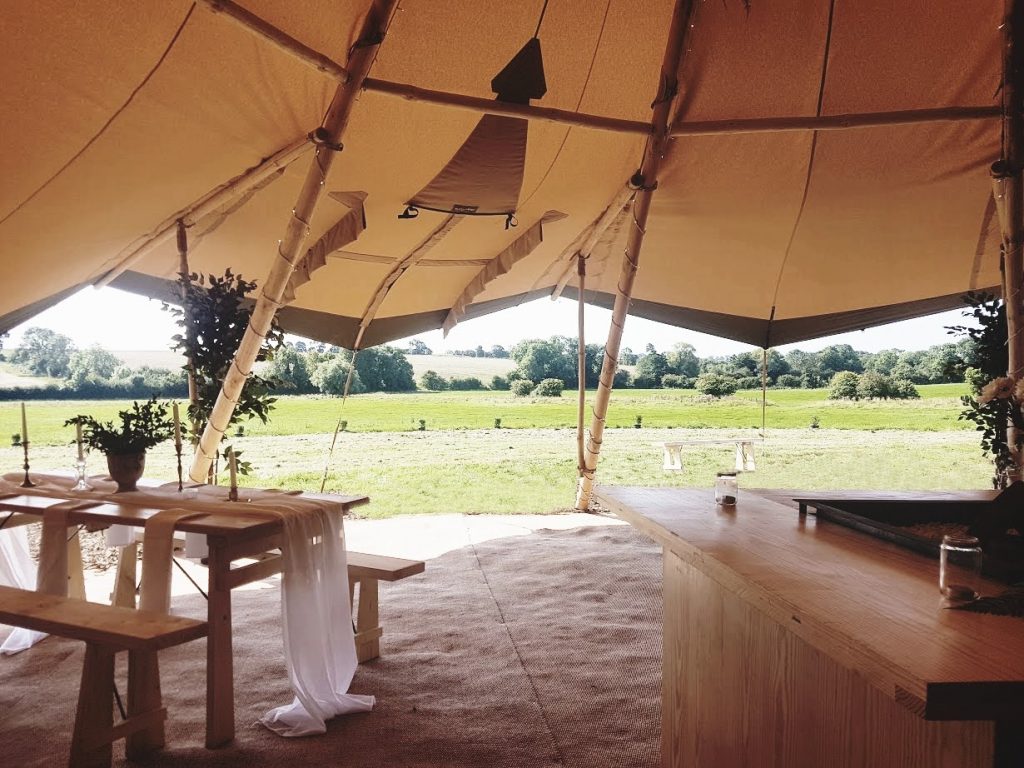 Shot of a wedding tipi at The Reid Rooms. A table is laid with soft white linen and the fields beyond are very rural. Shot of a wedding tipi at The Reid Rooms. A table is laid with soft white linen and the fields beyond are very rural.