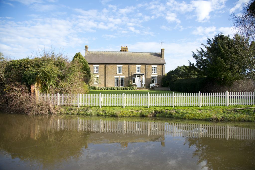 Exterior shot of Marks Hall Farmhouse, the on-site accommodation at The Reid Rooms. A large brick building with a moat and gardens surrounding it. Exterior shot of Marks Hall Farmhouse, the on-site accommodation at The Reid Rooms. A large brick building with a moat and gardens surrounding it.